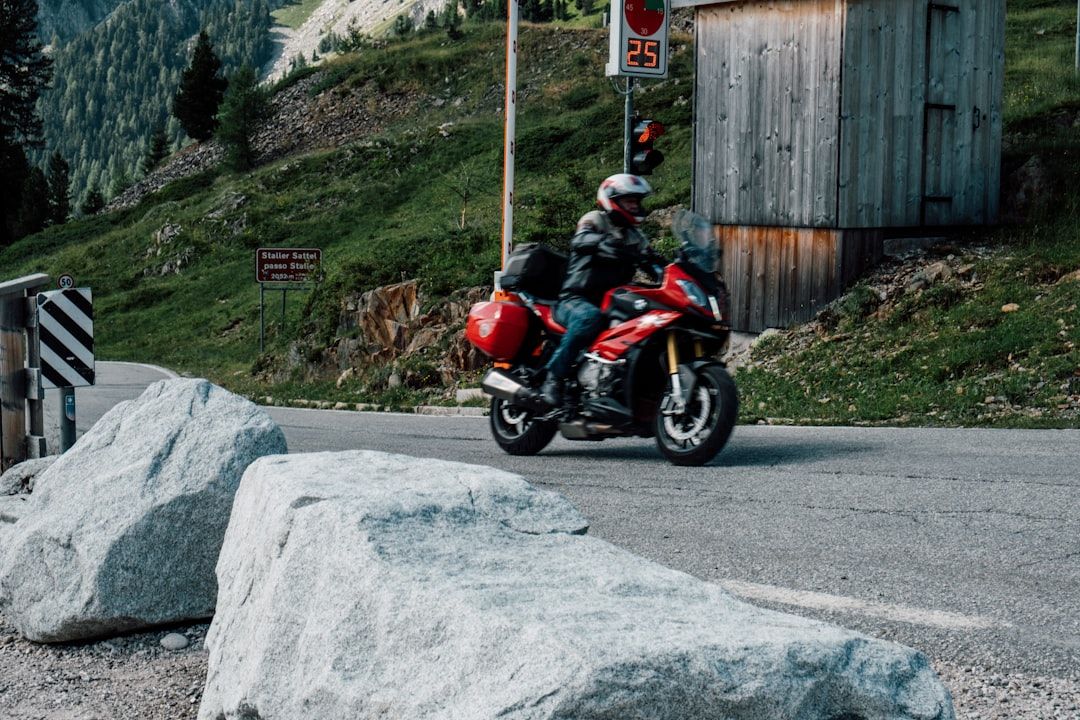 A motorcyclist riding a red touring bike on a winding alpine pass in Switzerland.